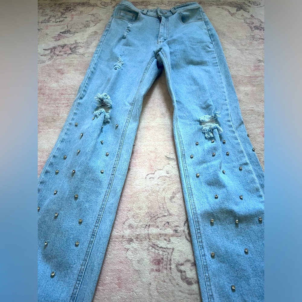 Distressed jeans with studs below the knee